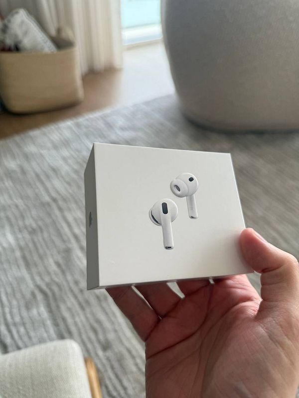 A person holds a new box of AirPods Pro 3 in a cozy indoor setting.