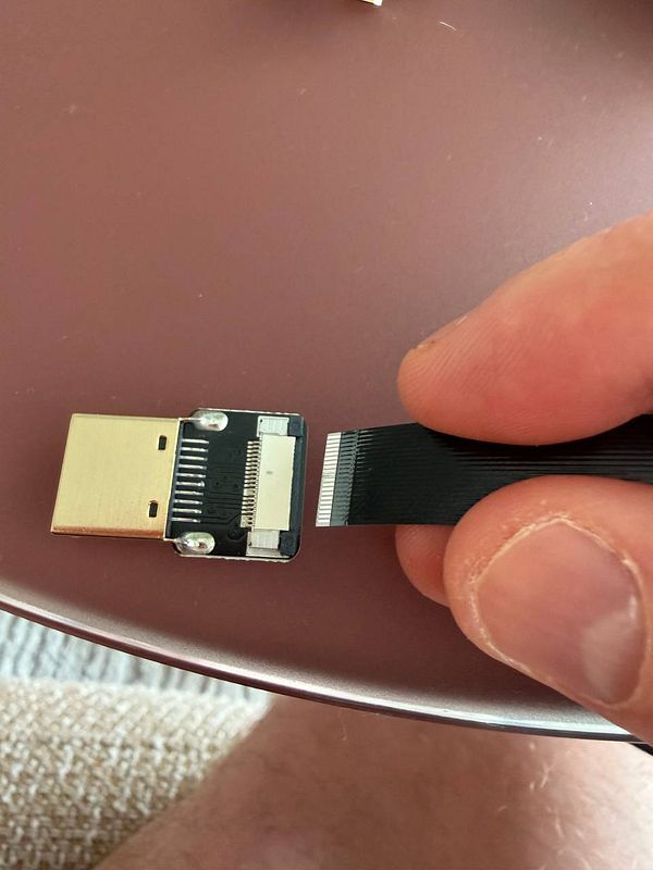 A person is connecting a ribbon cable to a USB device.