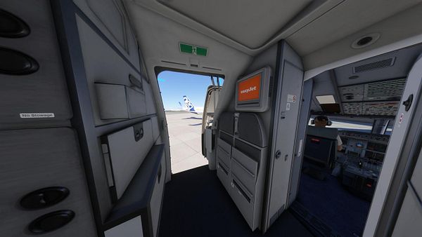 The image captures the interior of an aircraft, focusing on the cockpit area and the cabin entrance.