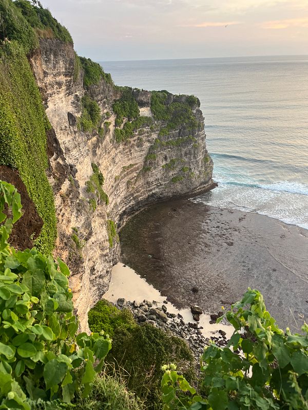 A stunning coastal view of Uluwatu featuring steep cliffs and a serene beach.