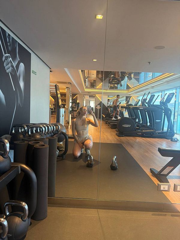 A woman is exercising with weights in a gym environment filled with fitness equipment.