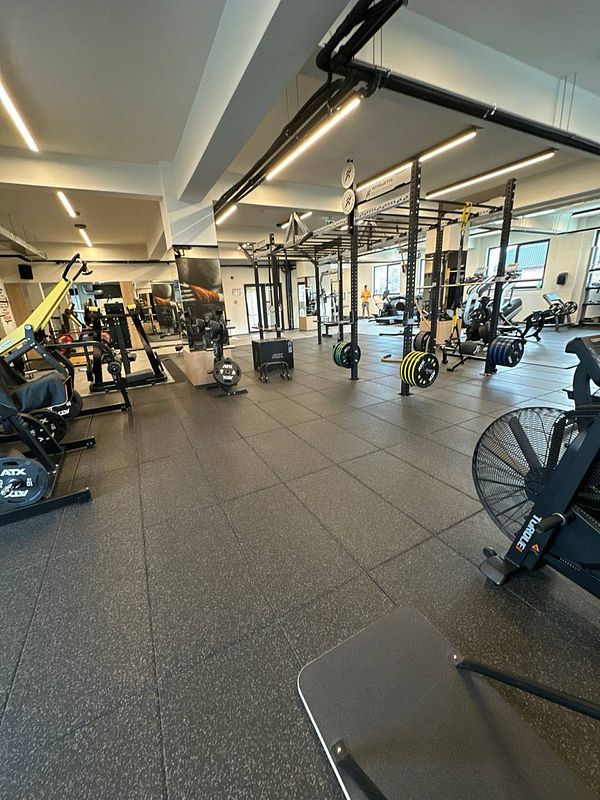 A spacious gym interior featuring various workout equipment and a clean, modern design.