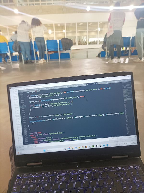 A laptop displaying code is positioned in the foreground, with a swimming competition taking place in the background.