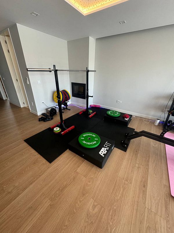 A home gym setup featuring weightlifting equipment and a clean, modern aesthetic.