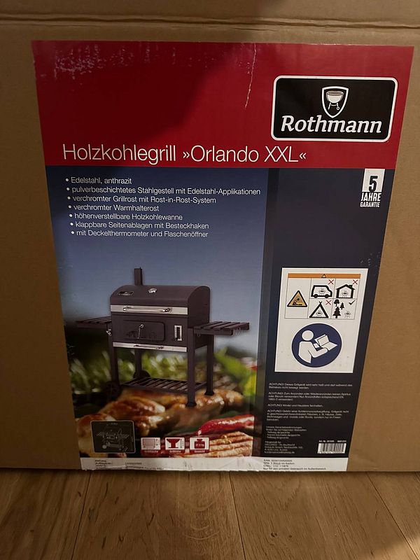 The image features the packaging of a Rothmann Orlando XXL charcoal grill.