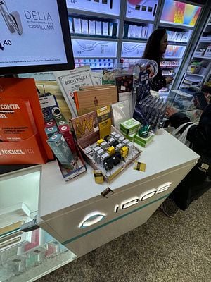 A retail display featuring various products, including IQOS items and stationery, with a customer browsing in the background.