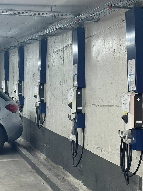 A row of electric vehicle chargers, all marked as out of service, in a parking garage.