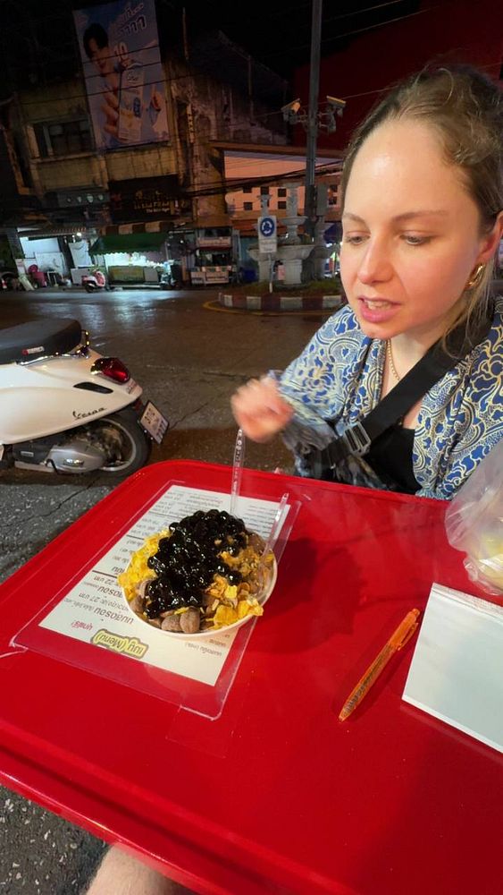 A serving of pang yen, a frozen bread dessert, cut into pieces in a red dish with a glass of milk beside it.