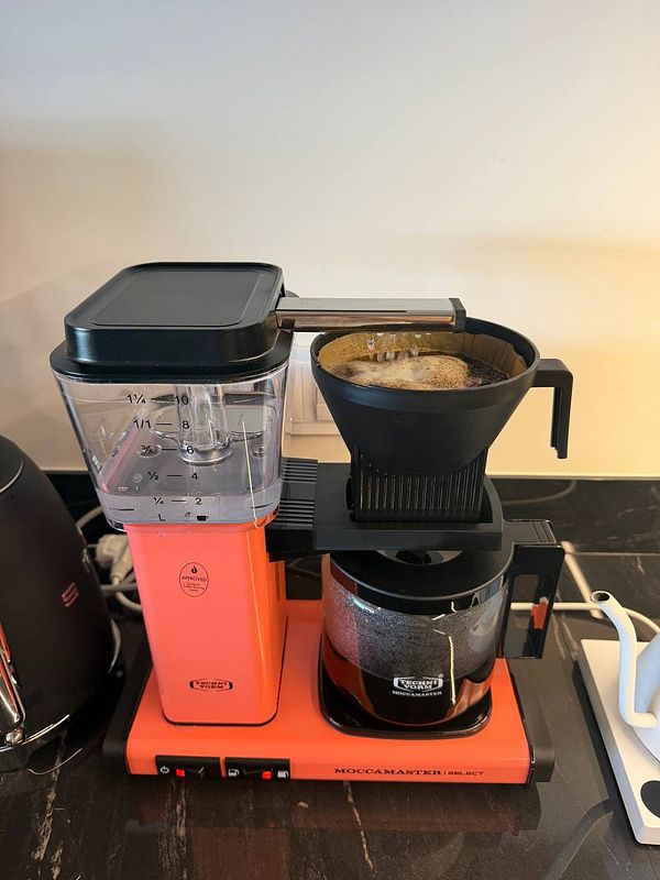 Moccamaster Select coffee maker brewing fresh coffee in a kitchen setting.