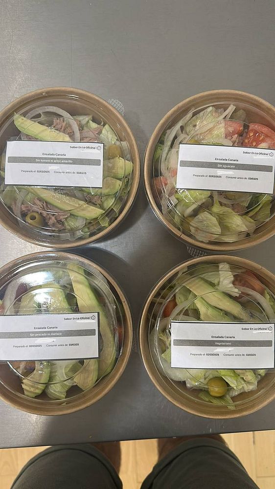Four salad containers with custom labels for catering deliveries.