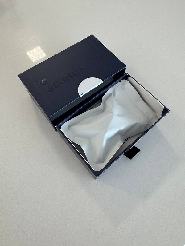 An open box containing a sleep erection sensor from Adam Health.