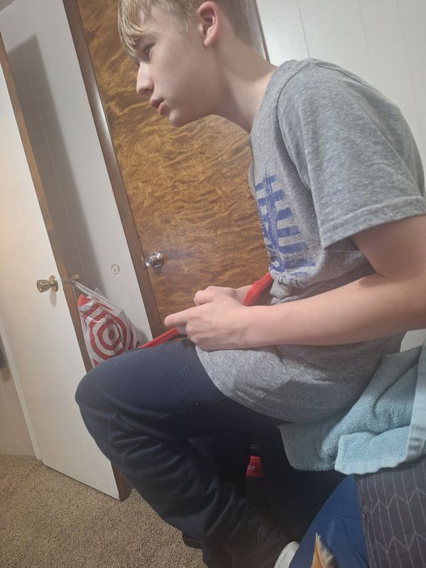 A retro NES controller in front of an NES console and game cartridges on a desk.