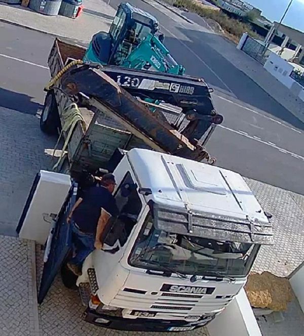 A truck driver is seen interacting with a damaged electric gate.