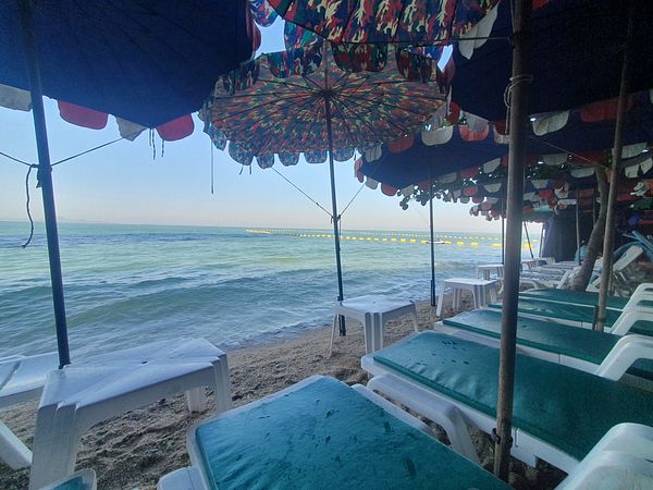 A serene beach scene featuring colorful umbrellas and lounge chairs.