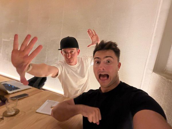 Two friends are taking a playful selfie in a casual setting.