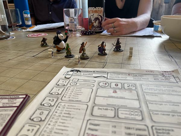 A tabletop gaming scene featuring miniatures and character sheets for a Dungeons & Dragons session.
