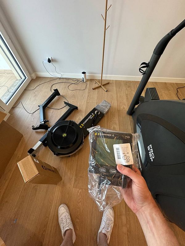 A home gym setup featuring a rowing machine and a fitness monitor.