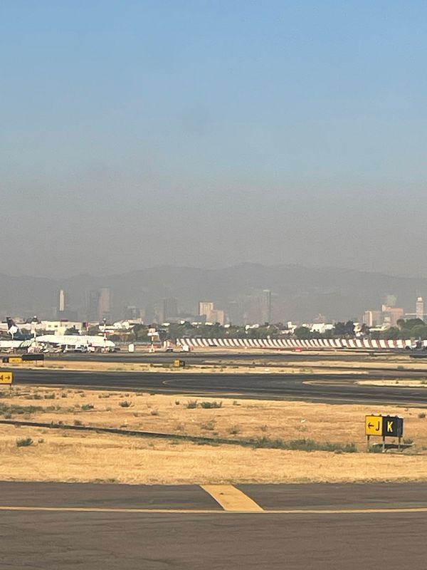 A view of Mexico City from an airport runway, highlighting a pollution cloud over the skyline.