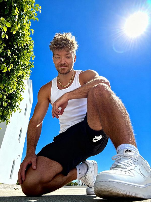 A young man poses in a fisheye perspective, showcasing a vibrant outdoor setting.