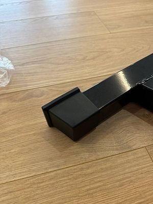 A close-up view of a black gym equipment component on a wooden floor.