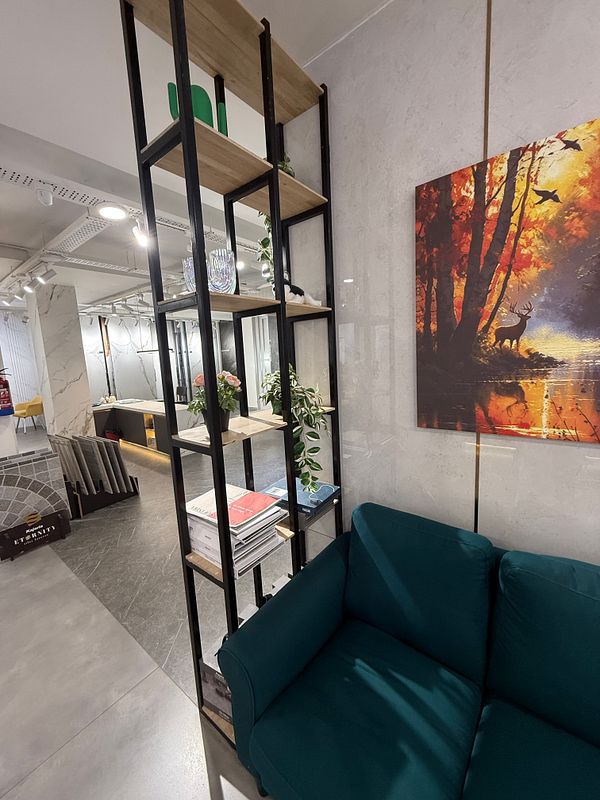 A modern interior space featuring a green couch, a decorative shelf, and a vibrant painting.