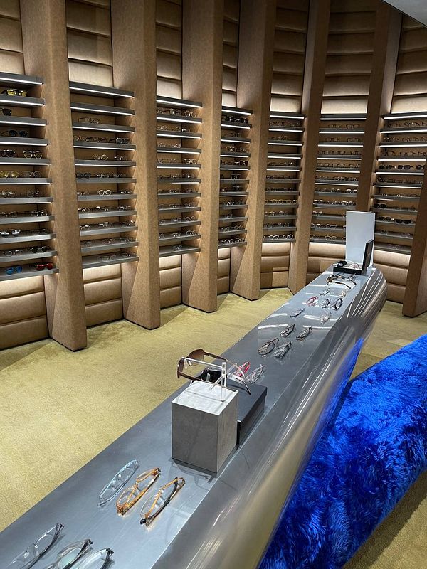 A stylish eyewear store featuring a variety of glasses displayed on sleek shelves and a modern counter.