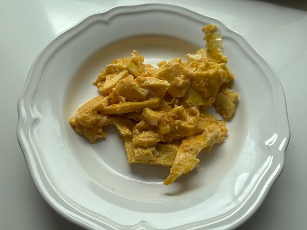 A plate of scrambled eggs is presented on a white dish.