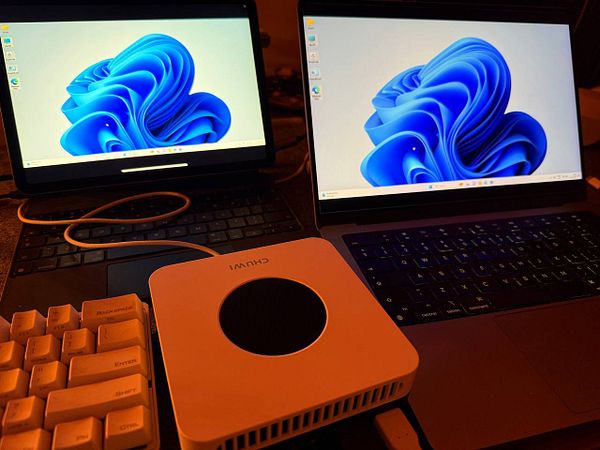 The image features a mini PC connected to an iPad and a laptop, both displaying a Windows interface.