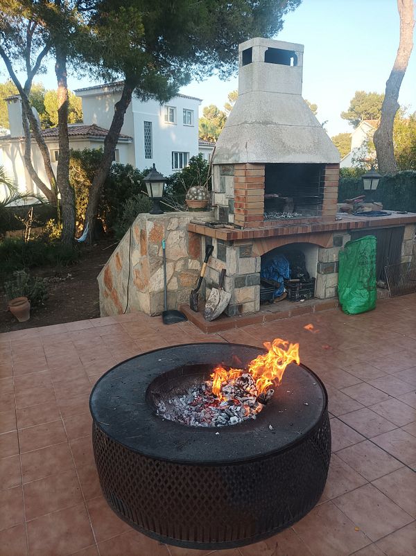 A cozy outdoor BBQ setup featuring a stone grill and a fire pit.