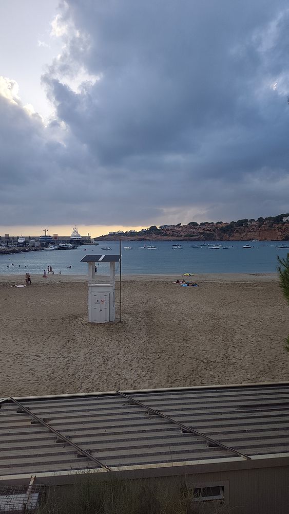 A photograph of a sandy beach under a partly cloudy blue sky.