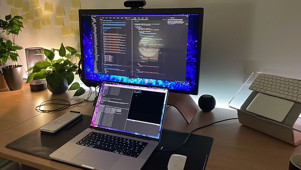 A well-organized coding workspace featuring a dual-monitor setup with a laptop and various tech accessories.