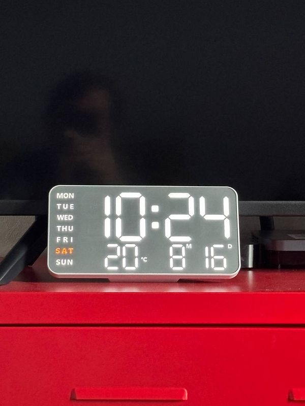 A digital clock displaying the time, temperature, and day of the week.