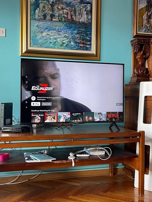 A modern TV displaying the Netflix interface with a movie currently playing.
