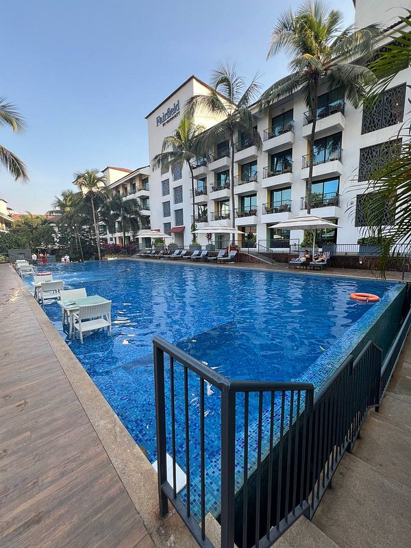 A serene swimming pool area at a hotel with palm trees and lounge chairs.