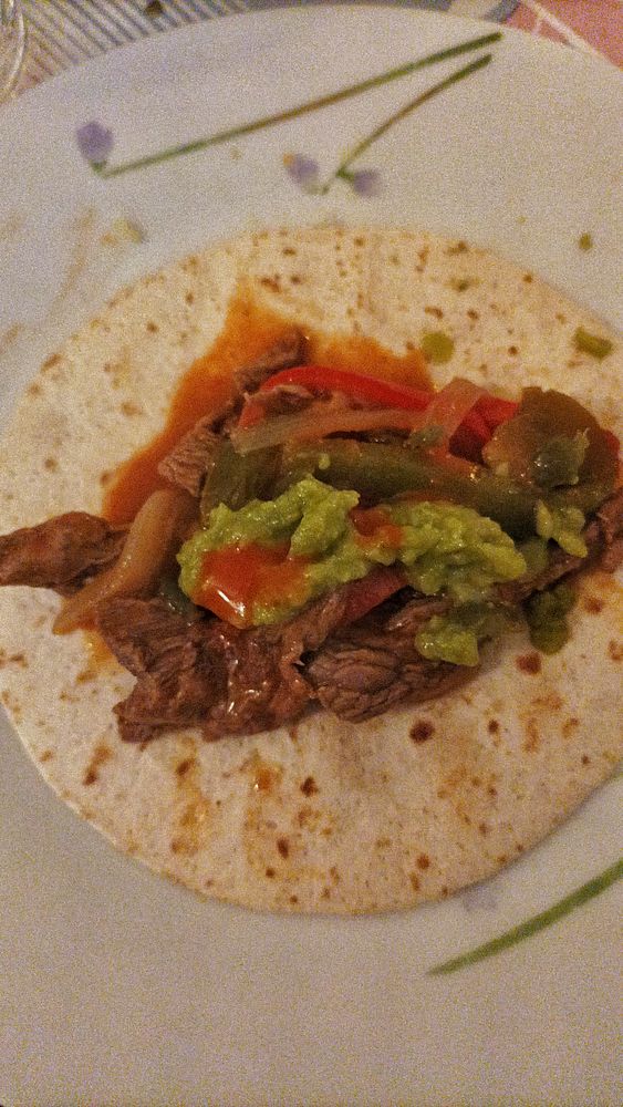 Close-up of a dish of cooked fajitas with grilled vegetables and tortillas.