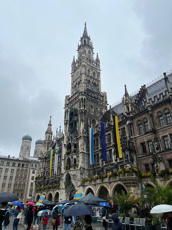 The image captures the iconic New Town Hall in Munich, showcasing its impressive architecture amidst a rainy atmosphere.