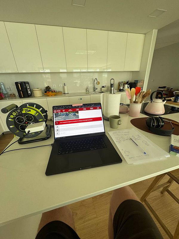 A workspace setup featuring a laptop, kitchen items, and a measuring tool.