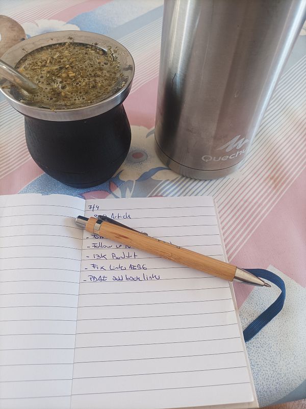 A cozy workspace featuring a traditional mate drink, a notebook with tasks, and a thermos.