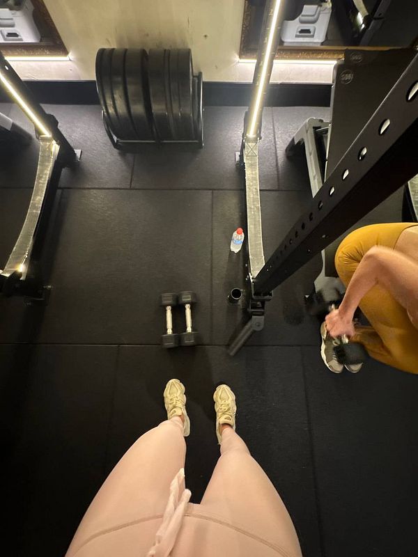 The image captures a gym setting from a top-down perspective, focusing on workout equipment and individuals exercising.