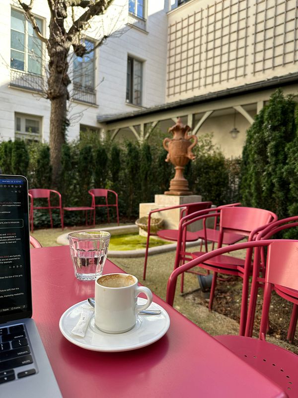 A cozy outdoor workspace featuring a coffee cup and a laptop in a garden setting.
