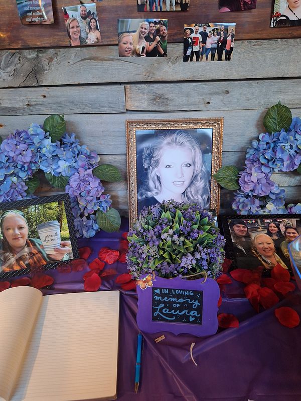 A memorial display honoring a friend with photographs, flowers, and a guestbook.