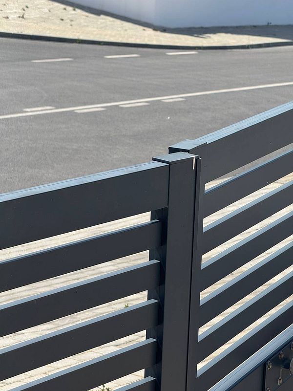 A damaged electric gate is partially visible, with a focus on its slatted design and the surrounding area.