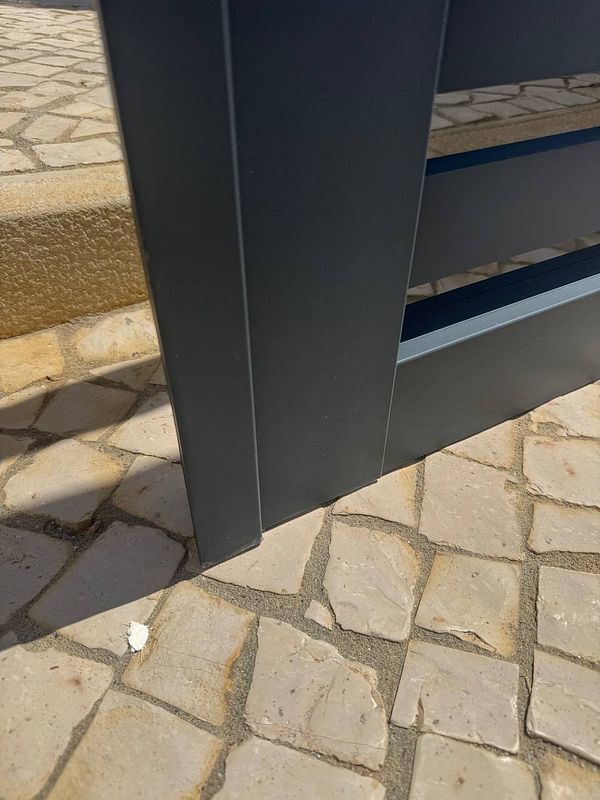 A close-up view of a damaged electric gate resting on the ground.