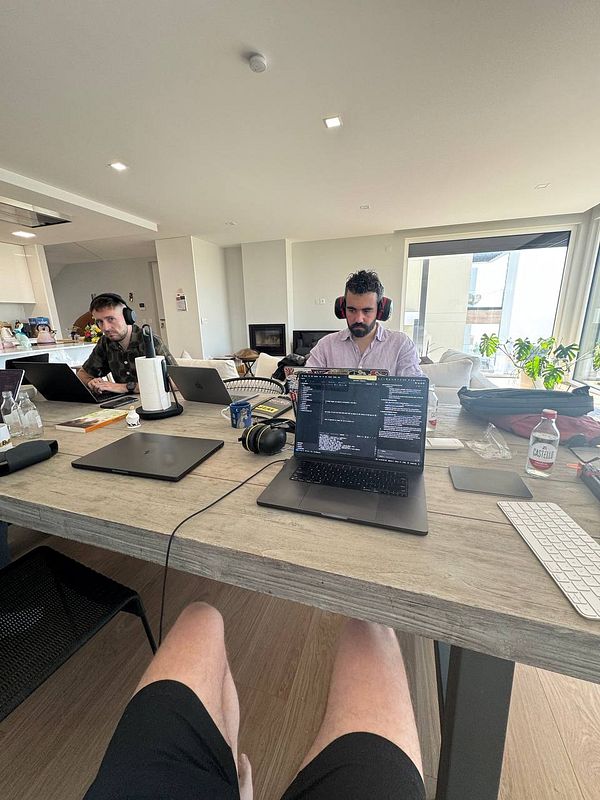 Two individuals are working at a shared table in a bright, modern coworking space.