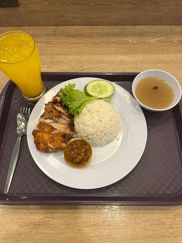 A plate of ayam penyet served with rice, vegetables, and a drink.