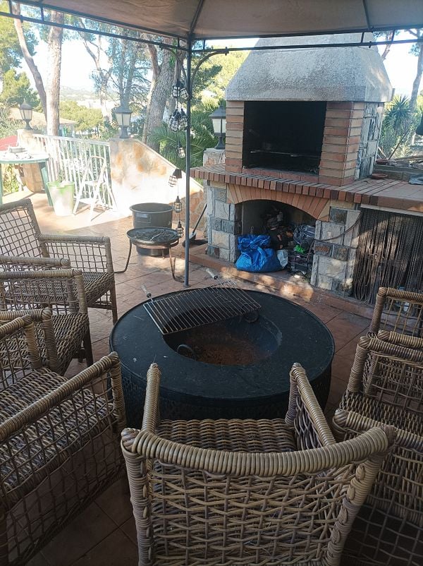 A cozy outdoor seating area featuring a fireplace and surrounding chairs.