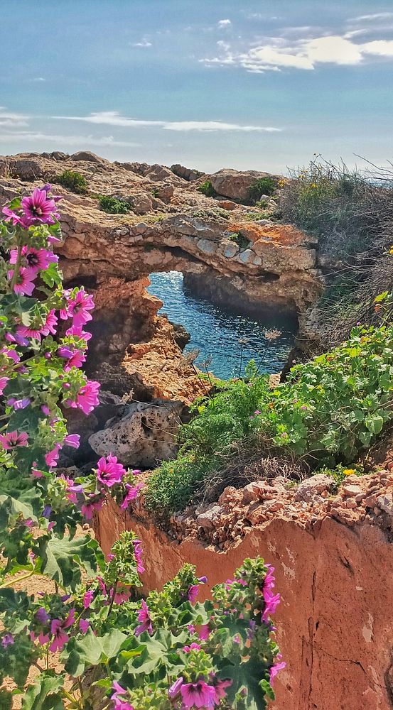A couple hiking on a rocky, snow-capped mountain under a clear blue sky.