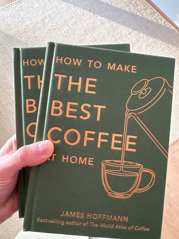 A person is holding two coffee books titled 'How to Make the Best Coffee at Home'.