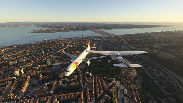 An aerial view of two aircraft flying over a coastal city at sunset.