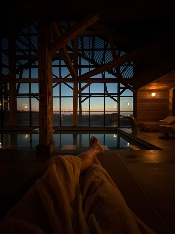 A serene indoor pool area with a view of a sunset over a rice field.